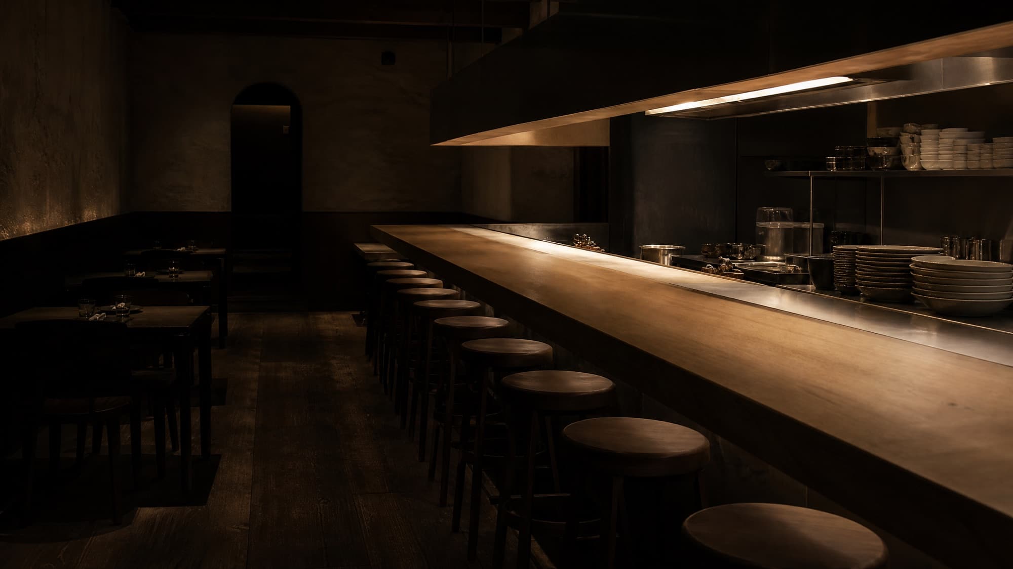 The dining room at Sfoglia before service, the counter and the open kitchen lit by the lamp over the pass.